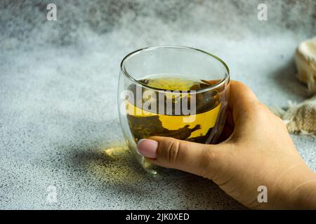 Feuilles de thé sencha vertes avec morceaux de mangue sur fond de béton Banque D'Images