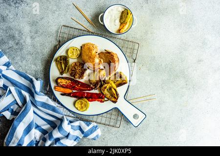 Un dîner sain avec une variété de légumes barbecue servi sur de la vaisselle en céramique avec une sauce à la crème aigre Banque D'Images
