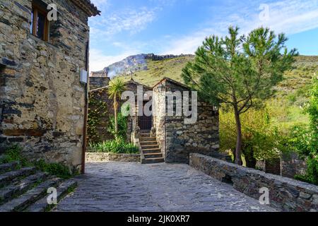 Petite maison de village à côté de la montagne et cheminée fumant le matin. Patones de Arriba Madrid. Espagne. Banque D'Images