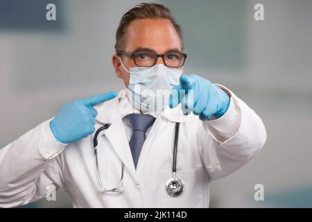 un médecin portant un masque médical et des gants médicaux fait un geste sur son équipement hygiénique Banque D'Images
