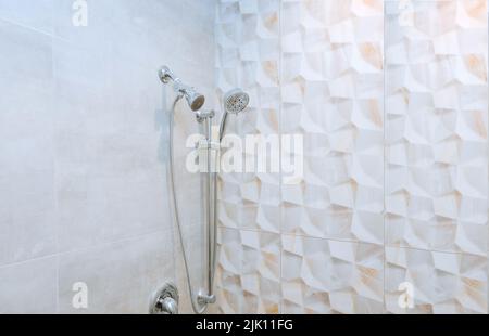 Gros plan d'une pomme de douche en acier inoxydable récemment installée sur le mur d'une salle de bains Banque D'Images