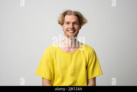 Portrait de l'homme hippster heureux, souriant et positif dans un t-shirt jaune regardant l'appareil photo, souriant sans souci sur fond blanc studio. Émotions. Banque D'Images