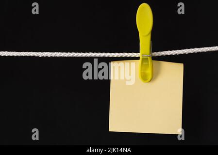 Den Helder, pays-Bas. Juillet 2022. Papier mémo vierge sur corde avec broche, sur fond noir. Isolé. Photo de haute qualité Banque D'Images