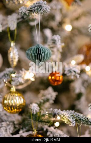 Gros plan d'un arbre de Noël décoré de boules et de lumières dorées et orange brillantes. Banque D'Images