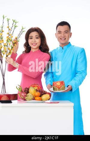 Un jeune couple heureux mettant de la nourriture et des branches d'abricot sur la table du dîner de vacances Banque D'Images