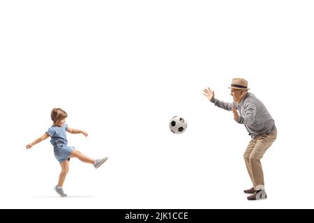 Photo pleine longueur d'une petite fille jouant au football avec un homme âgé isolé sur fond blanc Banque D'Images