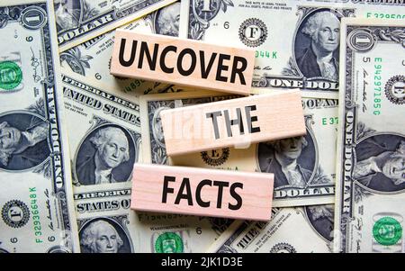 Uncover the facts symbol. Concept words Uncover the facts on wooden blocks on a beautiful background from dollar bills. Business and uncover the facts Banque D'Images