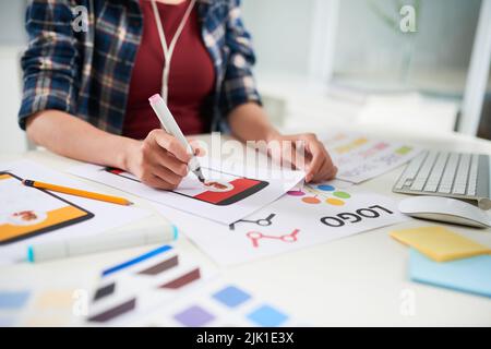 Gros plan d'un étudiant méconnaissable assis à un bureau et enveloppé dans un journal mural, arrière-plan flou Banque D'Images