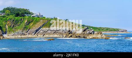 Vue panoramique d'un phare au sommet d'une falaise à côté de la mer par beau temps. Suances Santander. Banque D'Images