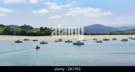 Vue sur la mer avec plage de sable blanc, bateaux et montagnes vertes en arrière-plan. Suances Santander. Banque D'Images