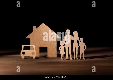 Découpez les figurines en carton d'une famille avec 2 enfants à côté d'une maison et d'une voiture. Assurance habitation et automobile. Protection de la famille Banque D'Images