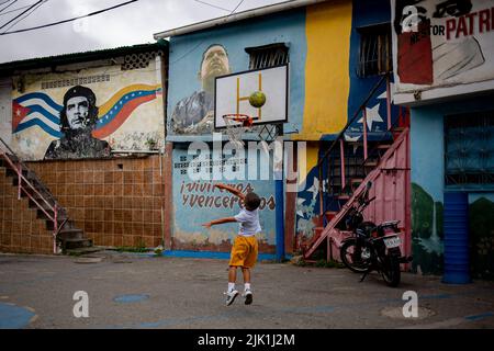 Caracas, Venezuela. 28th juillet 2022. Un enfant joue au basket-ball dans le quartier de 23 de Enero entouré de peintures murales représentant Ernesto Che Guevara, feu le président Hugo Chavez et des mottos tels que « nous vivrons et gagnerons ». Credit: Pedro Rances Mattey/dpa/Alay Live News Banque D'Images