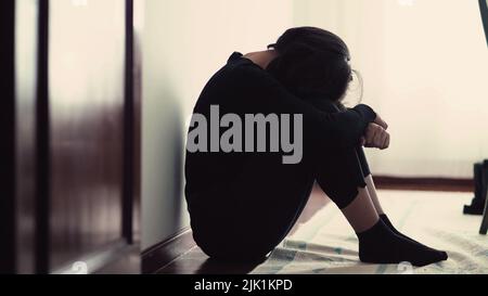 Personne dépressive et craintive assise sur le plancher recouvrant le visage en position fœtale. Femme désespérée se sentant désespéré et peur Banque D'Images