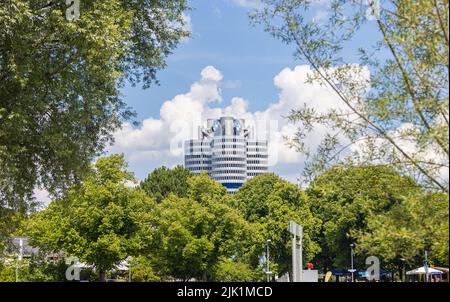 Munich, Allemagne - 6 juillet 2022 : le siège de BMW se présente sous la forme d'un moteur quatre cylindres derrière les arbres du parc olympique. La société lo Banque D'Images