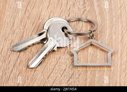 Porte-clés en forme de maison avec deux clés sur fond en bois Banque D'Images