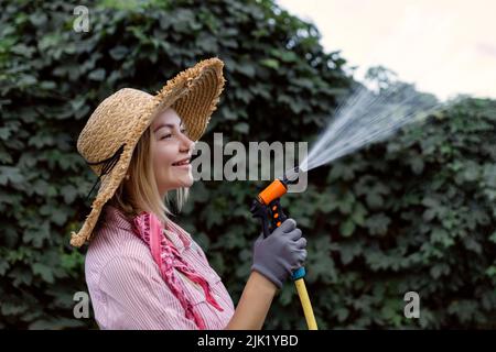 portrait de la jeune femme heureuse jardinier arrosoir jardin avec tuyau. Concept de passe-temps Banque D'Images