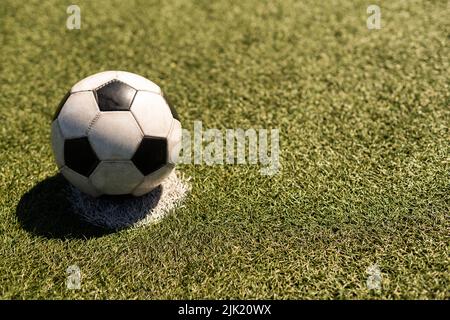 ballon de football blanc et noir sur fond d'herbe verte et de stade. idée de paris sportifs. Banque D'Images