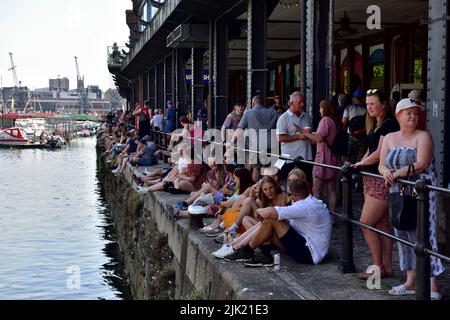 Foule de personnes assises à l'ombre le long du quai de Bristol Harbour lors d'une journée chaude ensoleillée pendant le festival du port, Royaume-Uni Banque D'Images