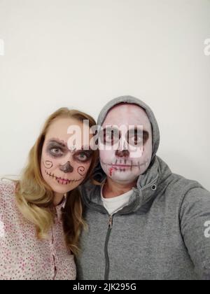 Jeunes gens avec un crâne peint sur leur visage sur un fond blanc. Célébration du jour des morts Banque D'Images