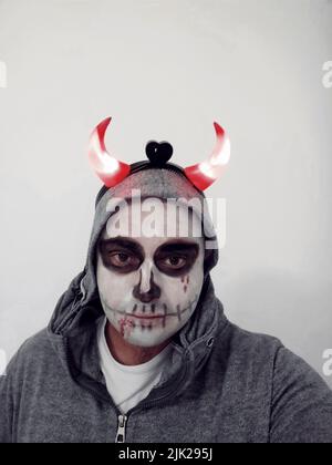 Un jeune homme avec un crâne peint sur son visage sur fond blanc. Célébration du jour des morts Banque D'Images