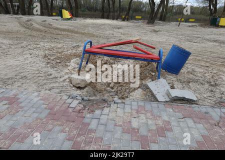 Cratère dans le parc après la chute d'obus d'artillerie, catastrophe écologique en Ukraine, obus russe a frappé un banc sur la plage, ville de Tchernihiv Banque D'Images