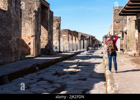 Un touriste sur une route pavée romaine typique de l'ancienne Pompéi, dans le sud de l'Italie Banque D'Images