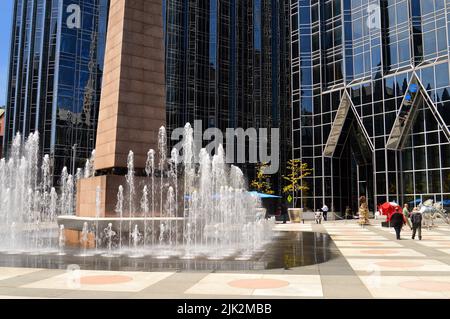 Des fontaines éclatent à PPG Plaza à Pittsburgh, en Pennsylvanie, tandis que les travailleurs des bâtiments voisins profitent de la lumière du soleil à l'heure du déjeuner Banque D'Images