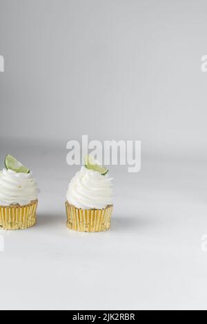 Cupcake au citron vert sur une table blanche, cupcake au citron vert avec crème blanche au beurre et un coin de citron vert, cupca à la margarita Banque D'Images