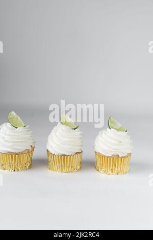 Cupcake au citron vert sur une table blanche, cupcake au citron vert avec crème blanche au beurre et un coin de citron vert, cupca à la margarita Banque D'Images