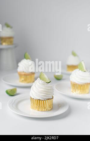 Cupcake de citron vert sur une assiette avec d'autres cupcakes en arrière-plan, cupcake de margarita avec crème blanche de beurre et un coin de lime, cupcake de margarita Banque D'Images