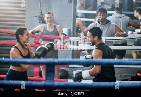 Actif, sain et en forme divers entraînement de groupe de boxe et de s'entraîner ensemble dans une salle de gym. Groupe sportif faisant un exercice de combat de force pendant que les gens Banque D'Images