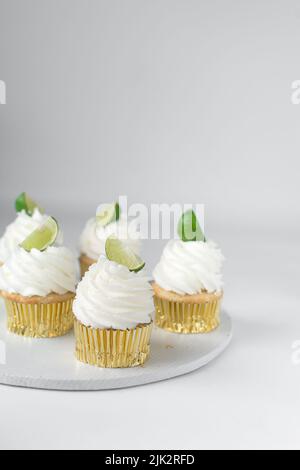 Cupcake au citron vert sur une table blanche, cupcake au citron vert avec crème blanche au beurre et un coin de citron vert, cupca à la margarita Banque D'Images