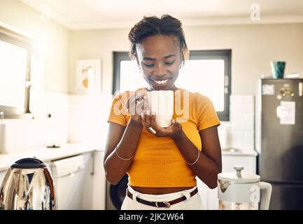 Belle, heureuse et détendue femme avec une tasse de café le matin après se réveiller le week-end à la maison. Jeune femme souriant, regardant et appréciant chaud Banque D'Images