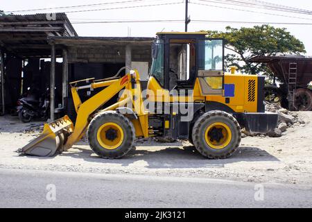 Niveleuse et excavatrice de bulldozer jaune équipement de construction avec découpe sur la rue Banque D'Images