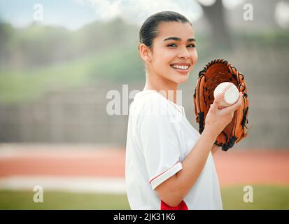 J'ai une présentation pour vous... Portrait court d'une jeune joueuse de baseball attirante debout à l'extérieur tout en portant un gant et tenant un baseball Banque D'Images