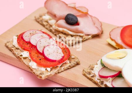 Différents pains à croûtes au jambon, à la tomate, au radis, au concombre et au fromage. Petit déjeuner facile. Alimentation. Sandwichs rapides et sains. Croustillant et garniture savoureuse. En-cas diététiques Banque D'Images