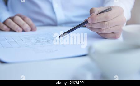 Il passe toujours par la paperasserie en profondeur. Un homme d'affaires méconnaissable passe par la paperasserie au travail. Banque D'Images