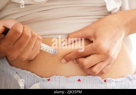 Retour à la normale de ses niveaux d'insuline. Gros plan d'une femme méconnue s'injectant dans l'estomac avec de l'insuline à la maison. Banque D'Images