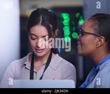 Ce qui est le pronostic. Deux jeunes femmes programmeurs d'ordinateur attrayant travaillant ensemble dans une salle de serveur. Banque D'Images