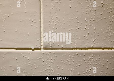 Gros plan sur les gouttelettes d'eau qui coulent le carrelage beige de la salle de bains Banque D'Images