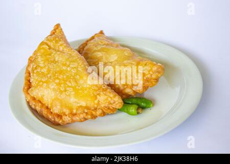 gâteau de pasties ou gâteau de pâtisserie ou kue pastel servi avec du piment vert dans une petite assiette sur fond de bois. gâteau indonésien pastel Banque D'Images