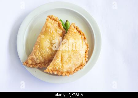 gâteau de pasties ou gâteau de pâtisserie ou kue pastel servi avec du piment vert dans une petite assiette sur fond de bois. gâteau indonésien pastel Banque D'Images