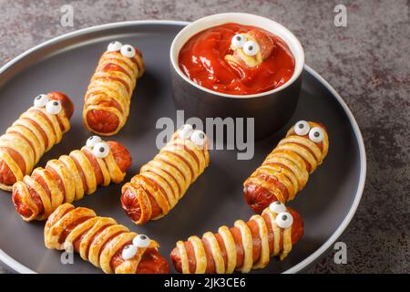 Saucisse cuite dans la pâtisserie momie nourriture pour Halloween partie ou les vacances des enfants dans l'assiette sur la table. Horizontale Banque D'Images