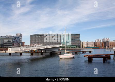 Yacht à voile passant par un pont tournant piétonnier mobile et moderne ouvert dans le port urbain avec des bâtiments et le ciel bleu en arrière-plan. Copier la flèche Banque D'Images