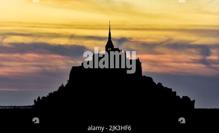 Silhouette du Mont Saint-Michel au coucher du soleil sur fond de coucher de soleil. Banque D'Images