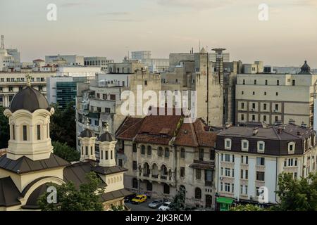 Bucarest, Roumanie - 30 juillet 2022 : ancienne partie de Bucarest pendant un coucher de soleil d'été avec des bâtiments neufs et anciens ensemble et le Palais du Parlement en t Banque D'Images