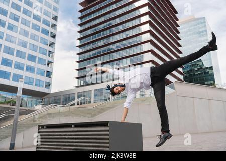 Homme d'affaires adulte heureux et séduisant portant un costume élégant faisant acrobatic trick se déplace dans la ville, concept alternatif pour la publicité d'affaires avec Banque D'Images