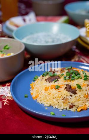 Pilaf ouzbek avec de la viande sur une assiette bleue sur la table. Banque D'Images