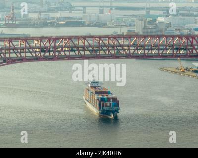 Vue aérienne d'un bateau-conteneur entièrement chargé entrant dans le port sous le pont Banque D'Images