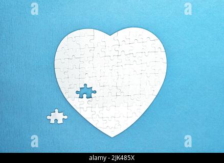 Puzzles blanches forme de coeur sur fond bleu. Concept de soins de santé Banque D'Images